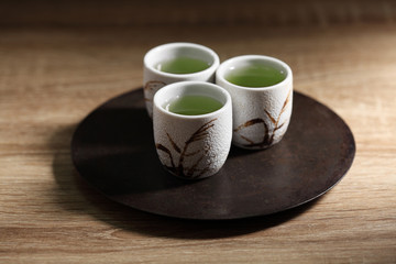 Japanese green tea in ceramic cup on wooden tray