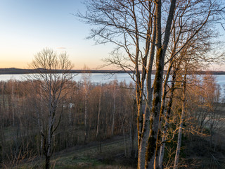 beautiful sunset landscape over the lake, charming evening colors, tree trunks in the foreground