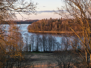 beautiful sunset landscape over the lake, charming evening colors, tree trunks in the foreground