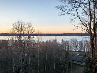 beautiful sunset landscape over the lake, charming evening colors, tree trunks in the foreground