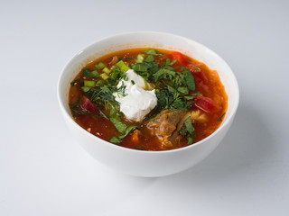 Borsch with sour cream in a white bowl on a white background. Side view