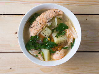 Fish soup in a white bowl. Salmon with potatoes and herbs. Top view