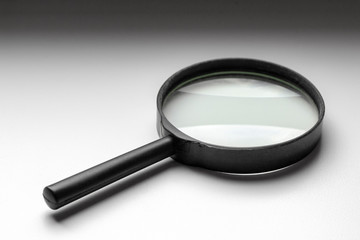 A black magnifier lies on a white windowsill.