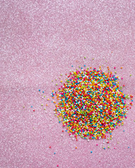 Colourful Sugar sprinkles, decoration for cake and ice-cream and cookies. Top view, Flat lay on pink glitter background.