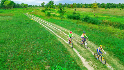 Family cycling on bikes outdoors aerial view from above, happy active mother with children have fun, family sport and fitness
