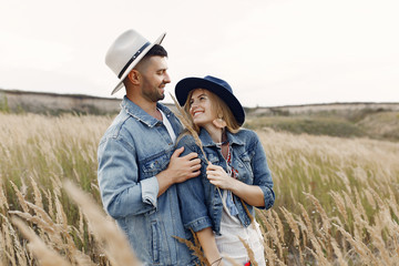 Naklejka na ściany i meble Loving couple in a wheat field. Beautiful blonde in a blue hat.