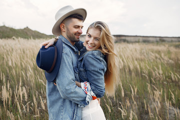 Loving couple in a wheat field. Beautiful blonde in a blue hat.