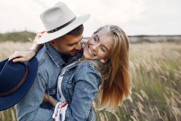 Loving couple in a wheat field. Beautiful blonde in a blue hat.