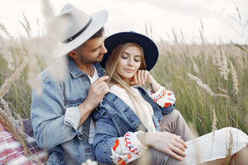Loving couple in a wheat field. Beautiful blonde with her boyfrinds. They sitting on a blanket
