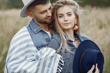 Loving couple in a wheat field. Beautiful blonde in a blue hat.