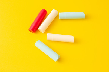 Multi-colored tubes with hygienic lipstick on a bright yellow background