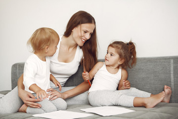 Cute family in a room. Lady in a white shirt. Mother with cute children