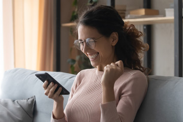 Head shot emotional young woman in glasses looking at mobile screen, amazed by good news...