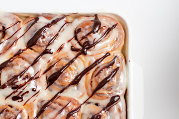 Freshly baked homemade cinnamon rolls in a baking dish on white background
