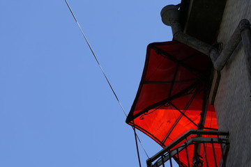Against the background of a clear, clear sky - a curious balcony with a red plastic visor of a beautiful geometric shape is visible.