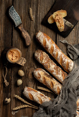 Fresh baked homemade crusty bread baguette. Two loaves and pate on wooden table. Top view.