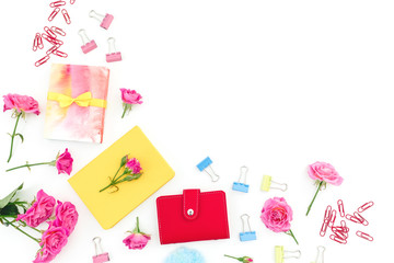 Female composition with notebook, clips, gift and roses lowers on white background. Flat lay. Top view
