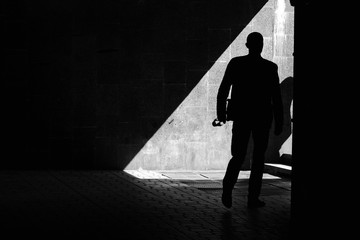 In a strip of bright light - a clear silhouette of a man walking in a tunnel.