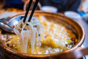 spicy chinese noodle with pork and vegetable in white bowl
