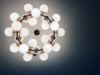 Lower angle view of bubble light bulb and golden metal chandelier on dark ceiling background.