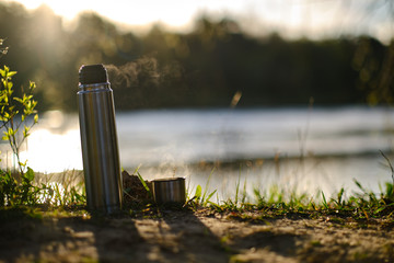 Thermal mug cup isolated with steam in nature setting with beautiful warm sunlight