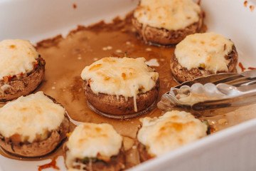 Freshly baked champignons with cheese and vegetables on a white plate