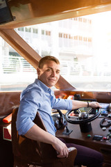 A man drives a sea pleasure boat A male captain of a watercraft boat at helm of a boat.