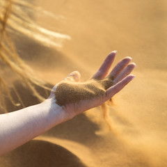 Desert sand on a female hand A girl holds hot sand in  desert in her hand. The wind blows sand out of  hands
