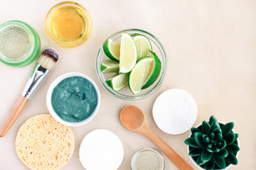 Preparing cosmetic facial mask purifying exfoliation with clay powder and lime citrus extract, homemade beauty treatment product, ingredients in bowls top view linen background