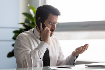 Frustrated businessman angry over bad news message talking on smartphone. Unhappy man employee...