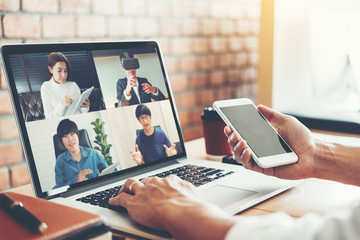 Fototapeta na wymiar Asian man working from home use Smart working and video conference online meeting with Asian team using laptop and tablet online in video call for new projects
