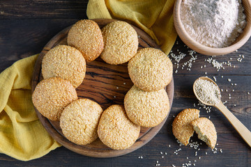 Freshly baked homemade sesame seed cookies on wooden board, rustic table. Healthy, tasty snack, honey seed bar, round form biscuits. Organic dessert, country style.