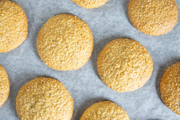 Freshly baked homemade sesame seed cookies on baking paper sheet after oven. Healthy, tasty snack, honey seed bar. Top view, flat lay. Cooking process.