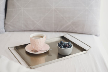 Breakfast in bed: coffee with milk and fresh blueberries on a metal tray. Weekend relax
