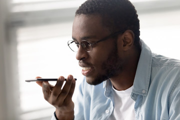 African american businessman talking for sound message recording. Smiling diverse man using...