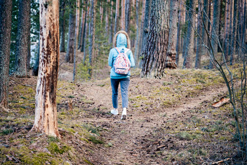 A lonely figure of a young woman hiking into the woods alone. The concept of being lonely and finding your own way.