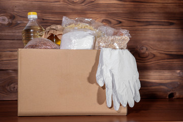Food delivery. Coronavirus food donation. Food in a box with gloves, closeup.