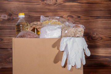 Coronavirus food donation. Food in a box with gloves, close-up. Food delivery.