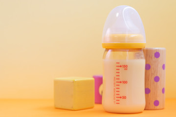 黄色の背景と哺乳瓶とおもちゃ