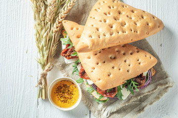 Tasty sandwich with dried tomatoes, arugula, red onion and cheese