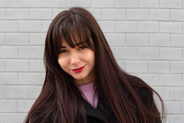 beautiful brunette against the background of a gray brick wall