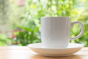 White coffee mug on wooden space background,  Back is a tree with a refreshing morning light.