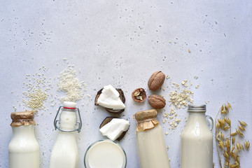 Alternative types of vegan milks in glass bottles. Top view with copy space. - obrazy, fototapety, plakaty