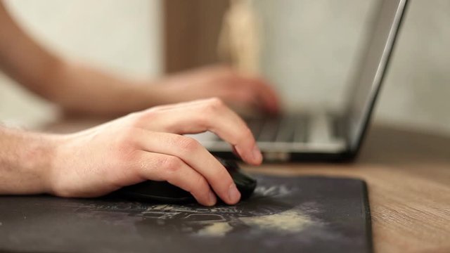 a man holds a computer mouse in his hand and uses it.