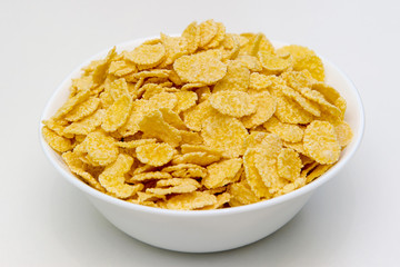 Bowl with healthy cornflakes on white background