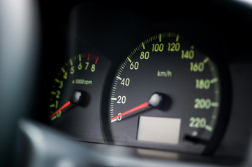 Close-up of the car dashboard, black speedometer, tachometer, with a red arrow indicating 0
