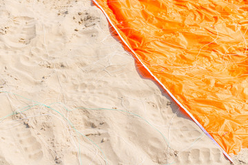 Orange vinyl kite surf lies down on the beach