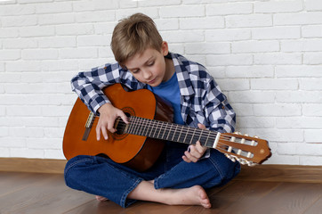 Handsome teenager playing at guitar at home