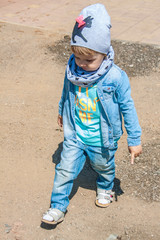 Happy baby walking on the city \ rural road. Bright spring photo. Child wearing jeans and jacket. Childhood, warm weather, happy toddler, walking independently, baby development concepts