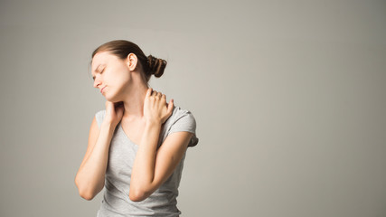 woman feeling neck pain, massaging tense muscles